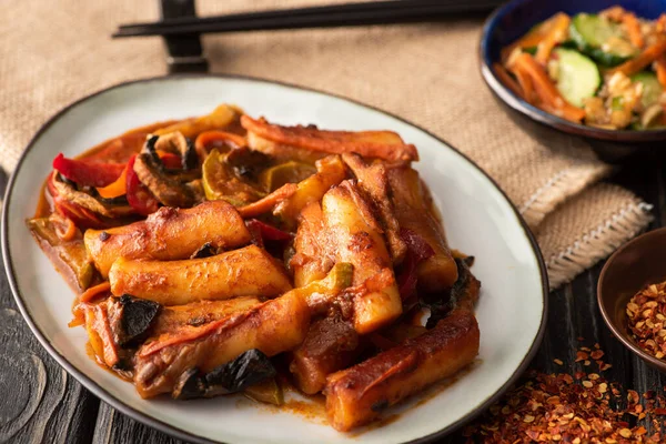 Selective focus of spicy topokki near dried chili pepper on wooden surface — Stock Photo