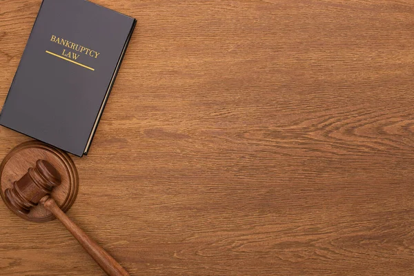 Vue du haut du livre de droit de la faillite et marteau sur fond en bois — Photo de stock