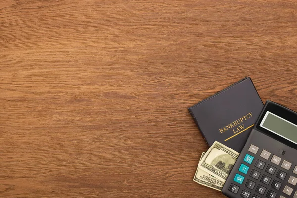 Vista superior do livro de direito de falência, dinheiro e calculadora em fundo de madeira — Fotografia de Stock