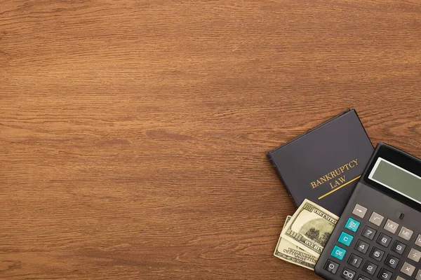 Vista superior del libro de leyes de bancarrota, el dinero y la calculadora sobre fondo de madera — Stock Photo