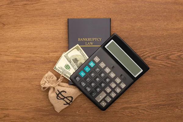 Top view of bankruptcy law book, cash and money bag, calculator on wooden background — Stock Photo