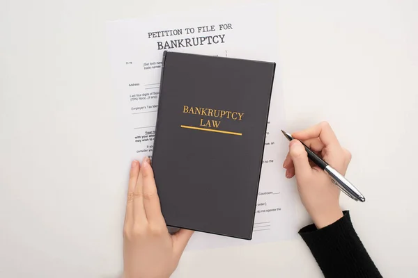 Vista recortada de la mujer con papel de bancarrota, libro de leyes y pluma sobre fondo blanco - foto de stock