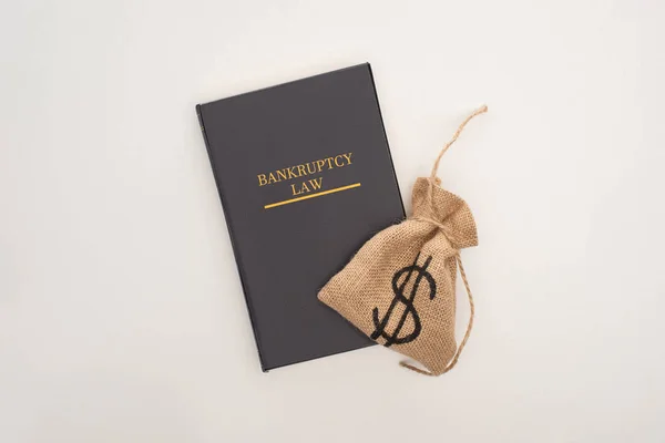 Vista dall'alto del libro di diritto fallimentare e sacchetto di denaro su sfondo bianco — Foto stock
