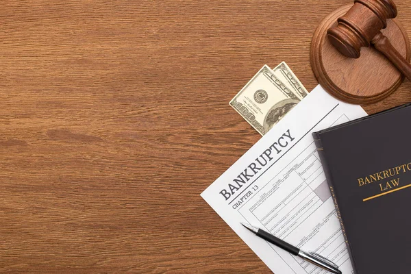 Top view of bankruptcy paper, law book, money and gavel on wooden background — Stock Photo