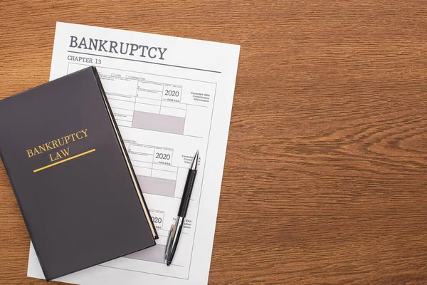 Top view of bankruptcy paper, law book and pen on wooden background — Stock Photo