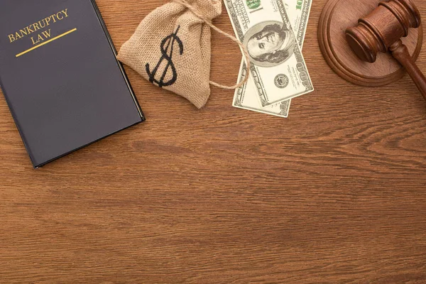 Vista superior del dinero, libro de leyes de bancarrota y martillo sobre fondo de madera - foto de stock