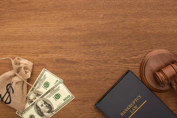Вид сверху на деньги, книгу закона о банкротстве и шапку на деревянном фоне — стоковое фото