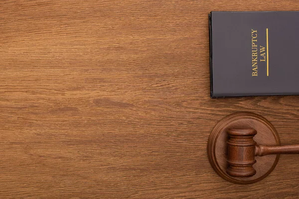 Top view of bankruptcy law book and gavel on wooden background — стоковое фото