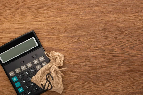 Vue du haut du sac d'argent, calculatrice sur fond en bois — Photo de stock