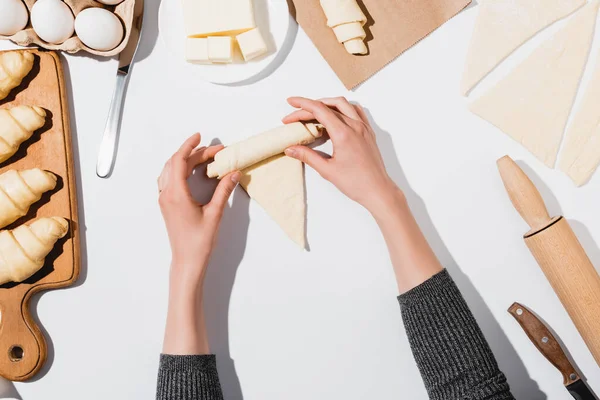 Cropped view of woman rolling croissant on white background — Stock Photo