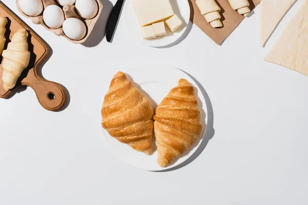 Draufsicht auf leckere gebackene Croissants auf Teller auf weißem Hintergrund — Stockfoto