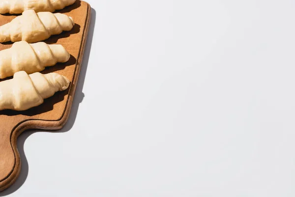 Raw fresh croissants on wooden cutting board on white background with copy space — Stock Photo