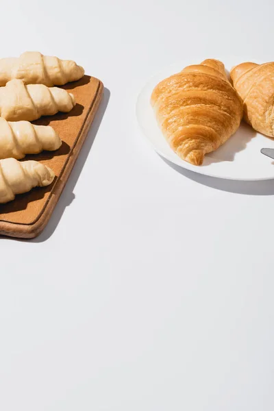 Fresh baked and raw croissants on white background — Stock Photo