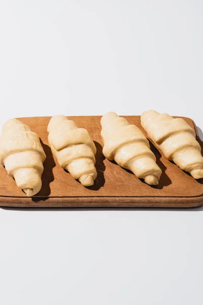 Croissants frais crus sur planche à découper en bois sur fond blanc — Photo de stock