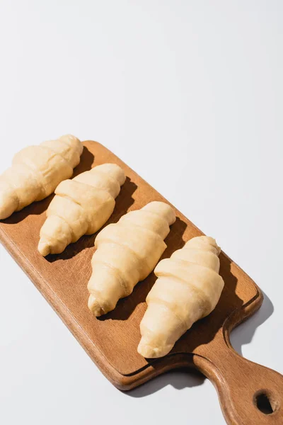 Croissants frais crus sur planche à découper en bois sur fond blanc — Photo de stock