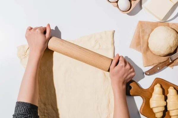 Zugeschnittene Ansicht einer Frau, die Teig für Croissants auf weißem Hintergrund ausrollt — Stockfoto