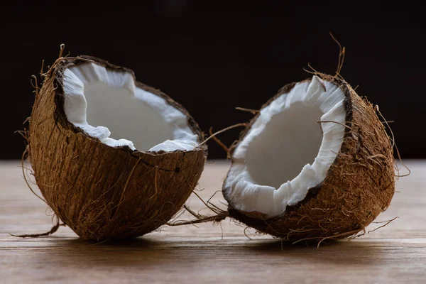 Fresh tasty coconut halves on wooden table isolated on black — Stock Photo