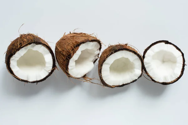 Vue de dessus des moitiés savoureuses fraîches de noix de coco sur fond blanc — Photo de stock