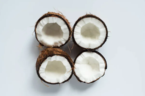 Vue de dessus des moitiés savoureuses fraîches de noix de coco sur fond blanc — Photo de stock