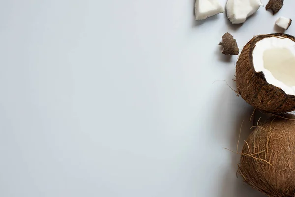 Draufsicht auf ganze und geknackte leckere Kokosnusshälften und -stücke auf weißem Hintergrund — Stockfoto