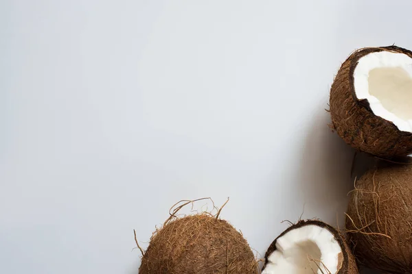 Вид сверху на свежие вкусные целые кокосы и половинки на белом фоне — стоковое фото
