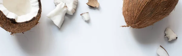 Top view of whole and cracked tasty coconut half and pieces on white background, panoramic shot — Stock Photo