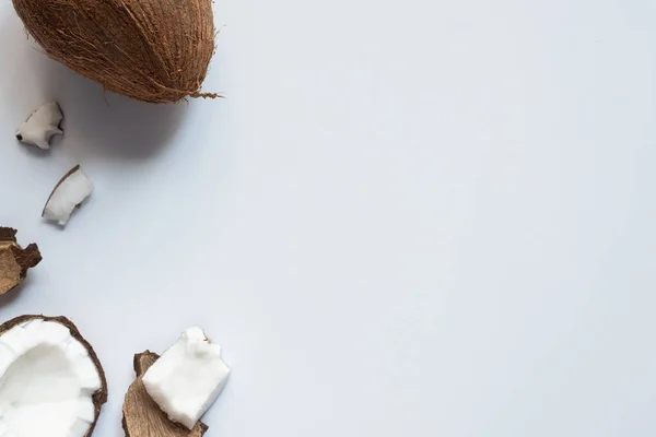 Draufsicht auf frische leckere ganze und geknackte Kokosnüsse auf weißem Hintergrund — Stockfoto