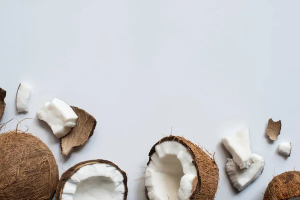 Вид сверху на свежий вкусный цельный и потрескавшиеся кокосы на белом фоне — стоковое фото