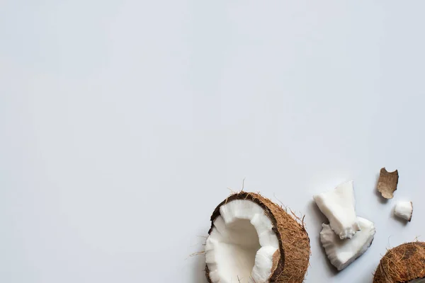 Vue de dessus de noix de coco fraîche savoureuse moitié et morceaux fissurés sur fond blanc — Photo de stock