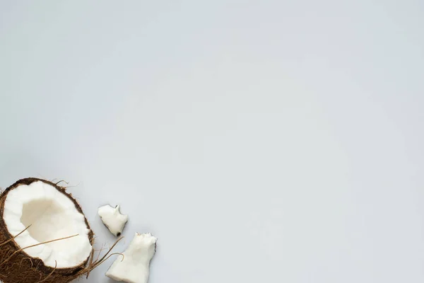 Vue de dessus de noix de coco fraîche savoureuse moitié et morceaux fissurés sur fond blanc — Photo de stock