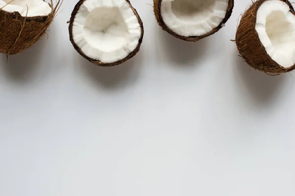 Vue de dessus des moitiés savoureuses fraîches de noix de coco sur fond blanc avec espace de copie — Photo de stock