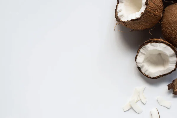 Вид сверху на свежие вкусные кокосовые половинки и хлопья на белом фоне — стоковое фото