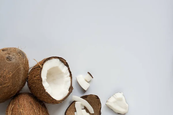 Draufsicht auf frische leckere geknackte Kokosnüsse mit Flocken und Schale auf weißem Hintergrund — Stockfoto