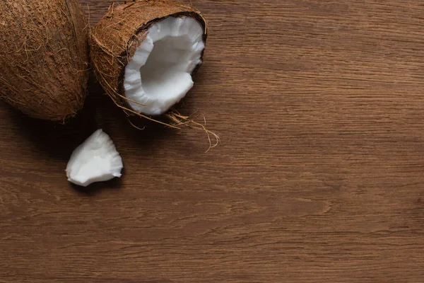 Vista superior de los cocos frescos sabrosos agrietados y enteros en la mesa de madera - foto de stock