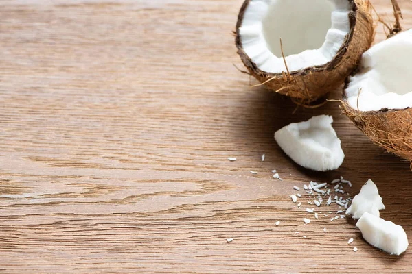 Fresh tasty whole and cracked coconuts and flakes on wooden table — Stock Photo