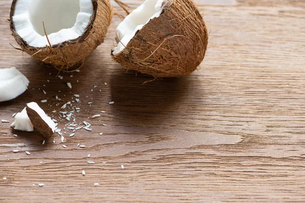 Fresh tasty whole and cracked coconuts and flakes on wooden table — Stock Photo