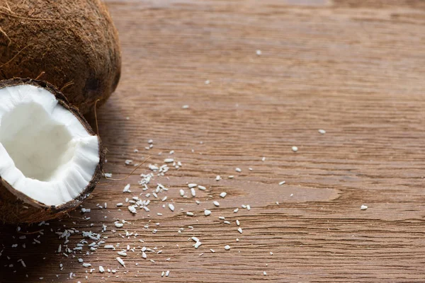 Fresh tasty whole coconut and half near flakes on wooden table — Stock Photo