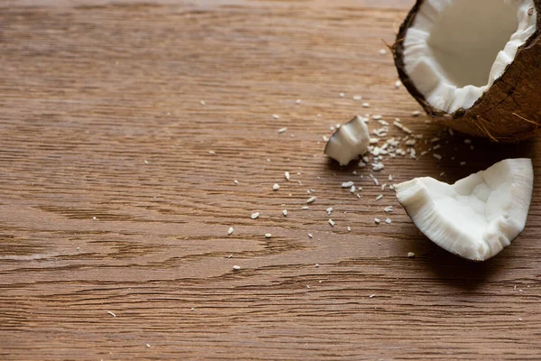 Frische leckere Kokosnuss halb in der Nähe von Flocken auf Holztisch — Stockfoto