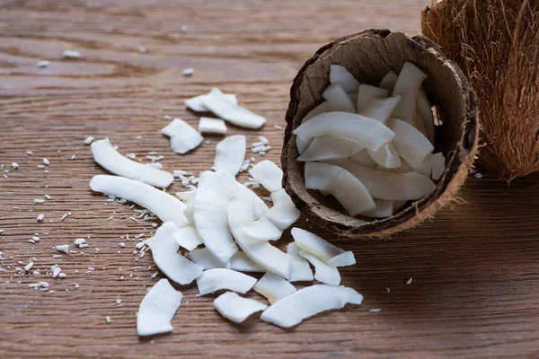 Fresh tasty coconut flakes in shell on wooden table — Stock Photo