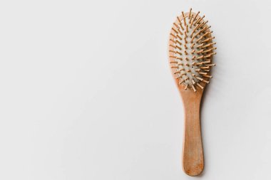 Hafif ahşaptan yapılmış ahşap bir tarak beyaz arka planda yatar..