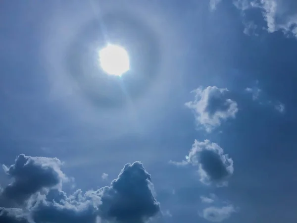 Голубое небо с облаками и круговым солнцем — стоковое фото