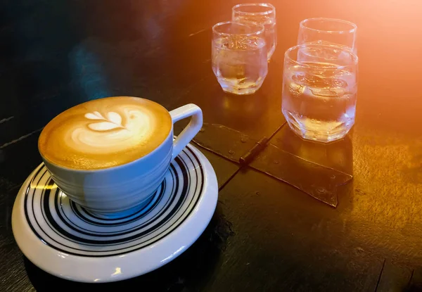 Hot Cappuccino och vatten på bordet med glas vatten — Stockfoto