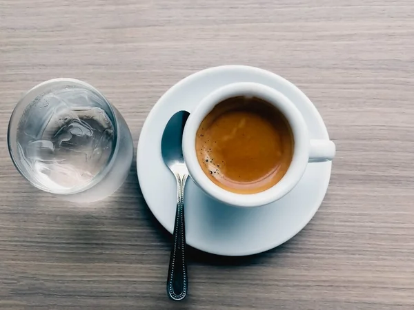 Espresso varm kaffe glas vatten och sked — Stockfoto