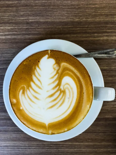 Tatlı sıcak cappuccino kaşık ile masada — Stok fotoğraf