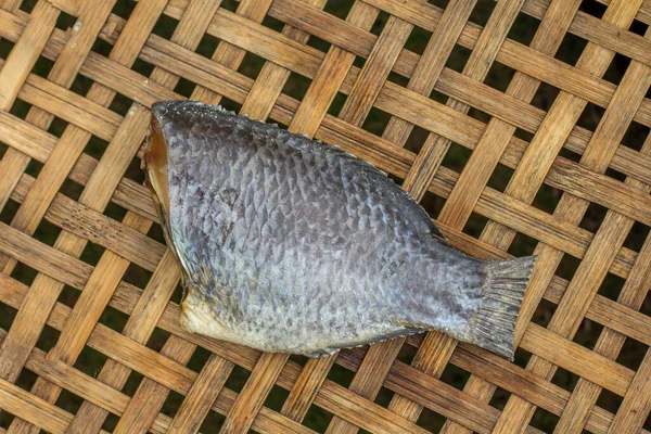 Thai food preservation. Preservation tilapia nile fish by cutting head.salted and dried in sunligh. on weave bamboo container, bamboo net.food Preservation concept