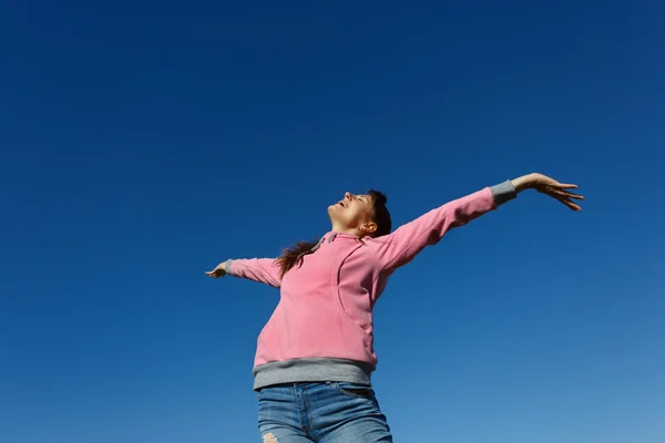 Mooie jonge vrouw tegen de blauwe hemel. — Stockfoto
