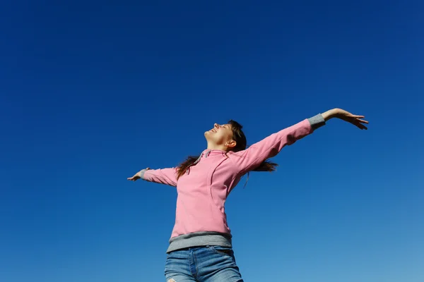 Mooie jonge vrouw tegen de blauwe hemel. — Stockfoto