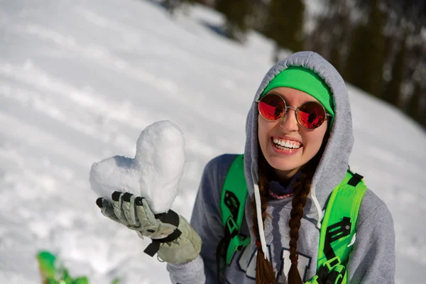 Retrato de niña snowboarder con corazón de nieve en las manos —  Fotos de Stock