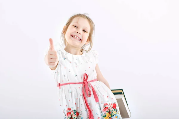 Ein kleines fröhliches Mädchen mit Schulbüchern. — Stockfoto