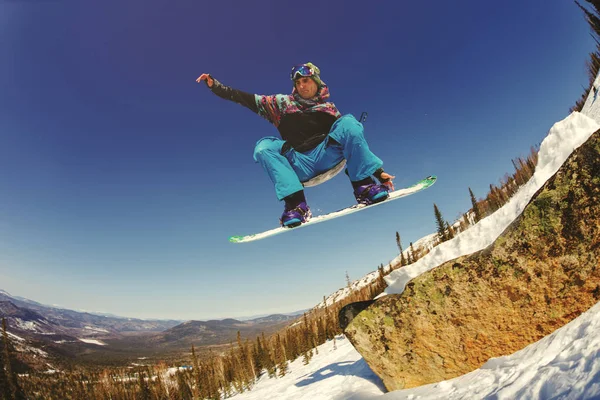 Snowboardåkare som hoppar från en språngbräda mot himlen — Stockfoto